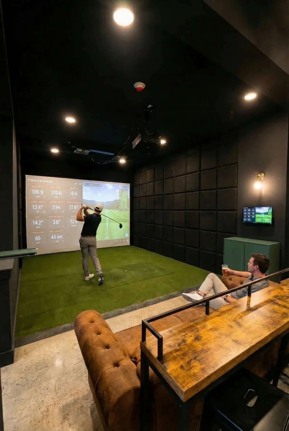 A member hitting while another watches from the lounge at Wood Lane